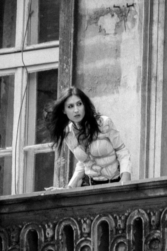 Woman in bondage looking out from a balcony