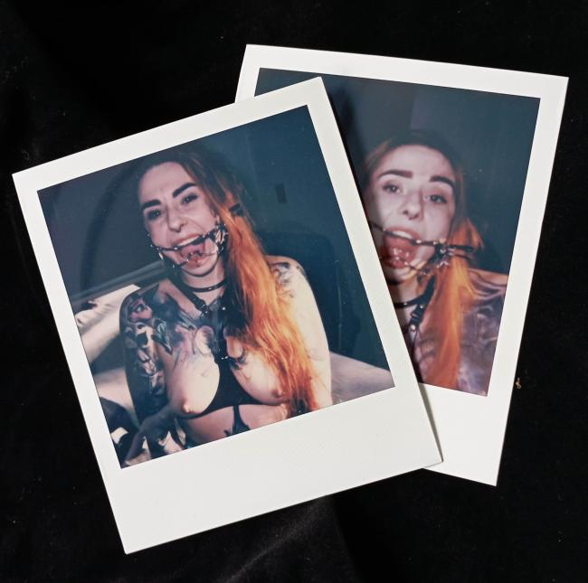 Woman wearing a BDSM gag harness in a sensual backstage setting, captured in Polaroid style