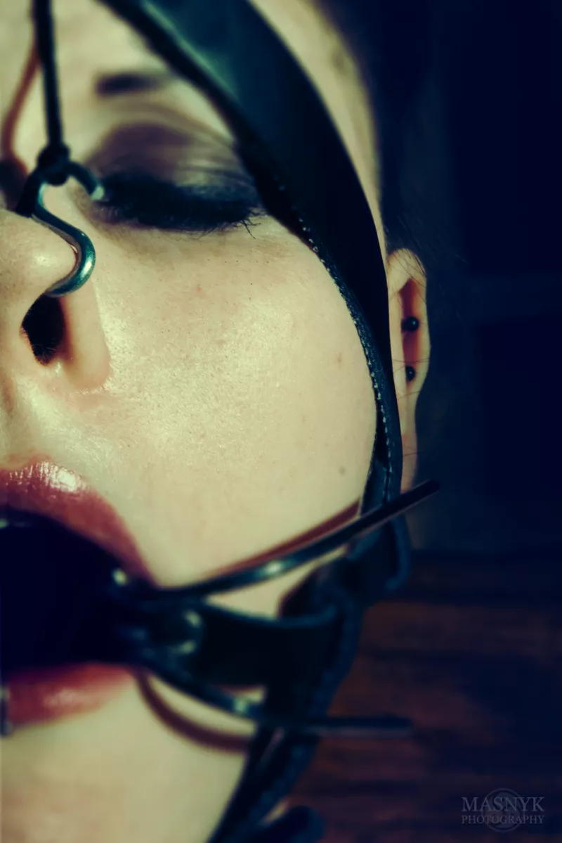 Unieruchomiona, zakneblowana dziewczyna z hakami w nosie