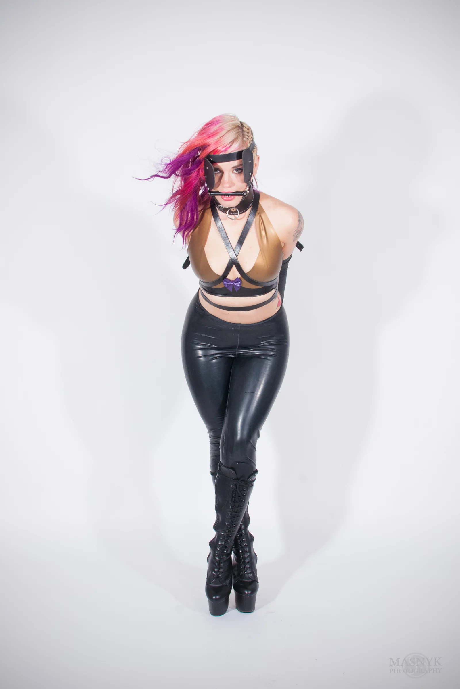 Zakneblowana kobieta w latexowym stroju w roli pony girl