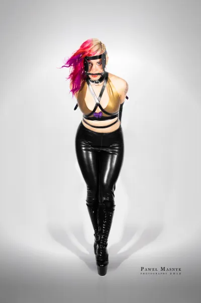Zakneblowana kobieta w latexowym stroju w roli pony girl