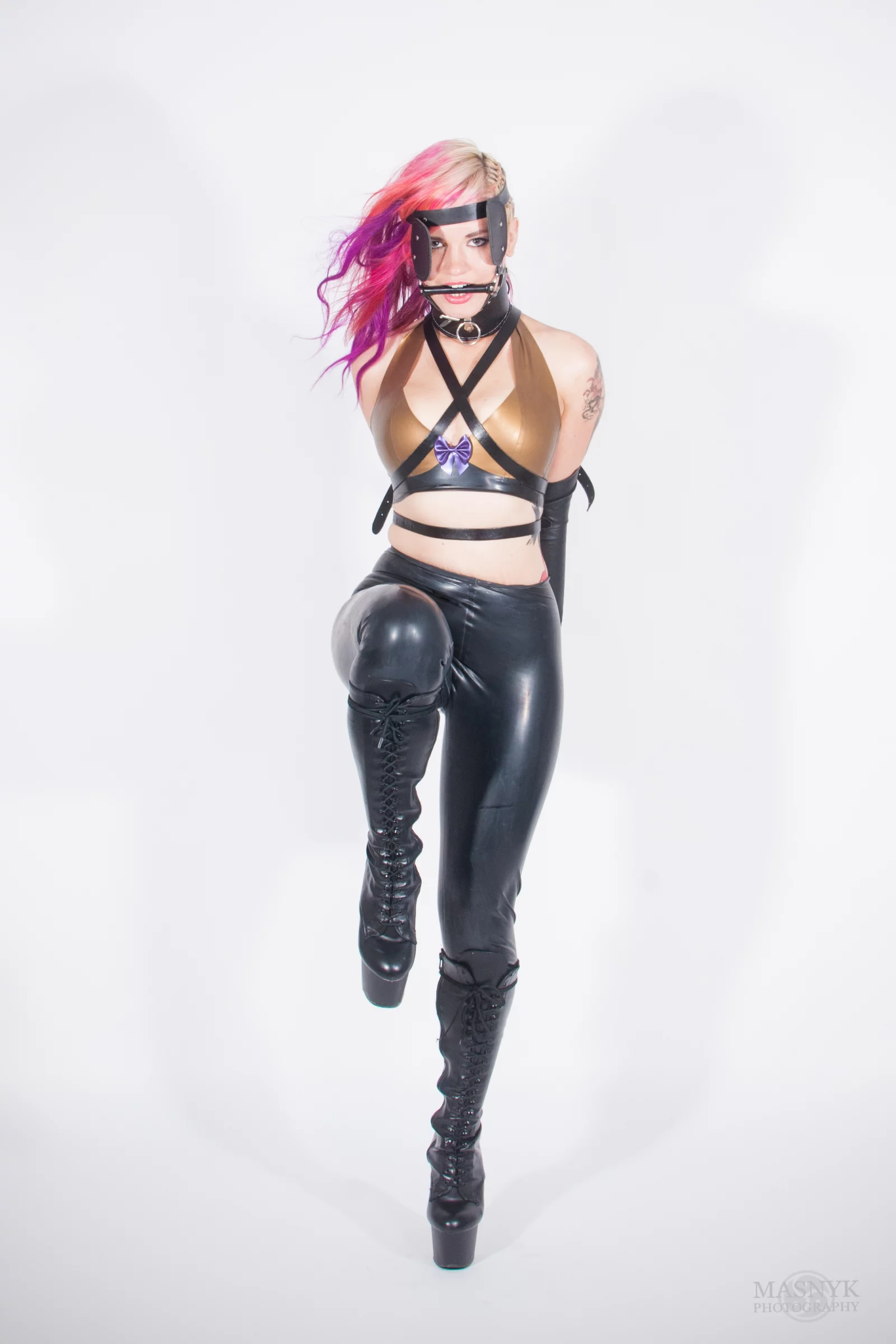 Zakneblowana kobieta w latexowym stroju w roli pony girl