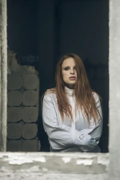 Rudowłosa w kaftanie bezpieczeństwa przy oknie