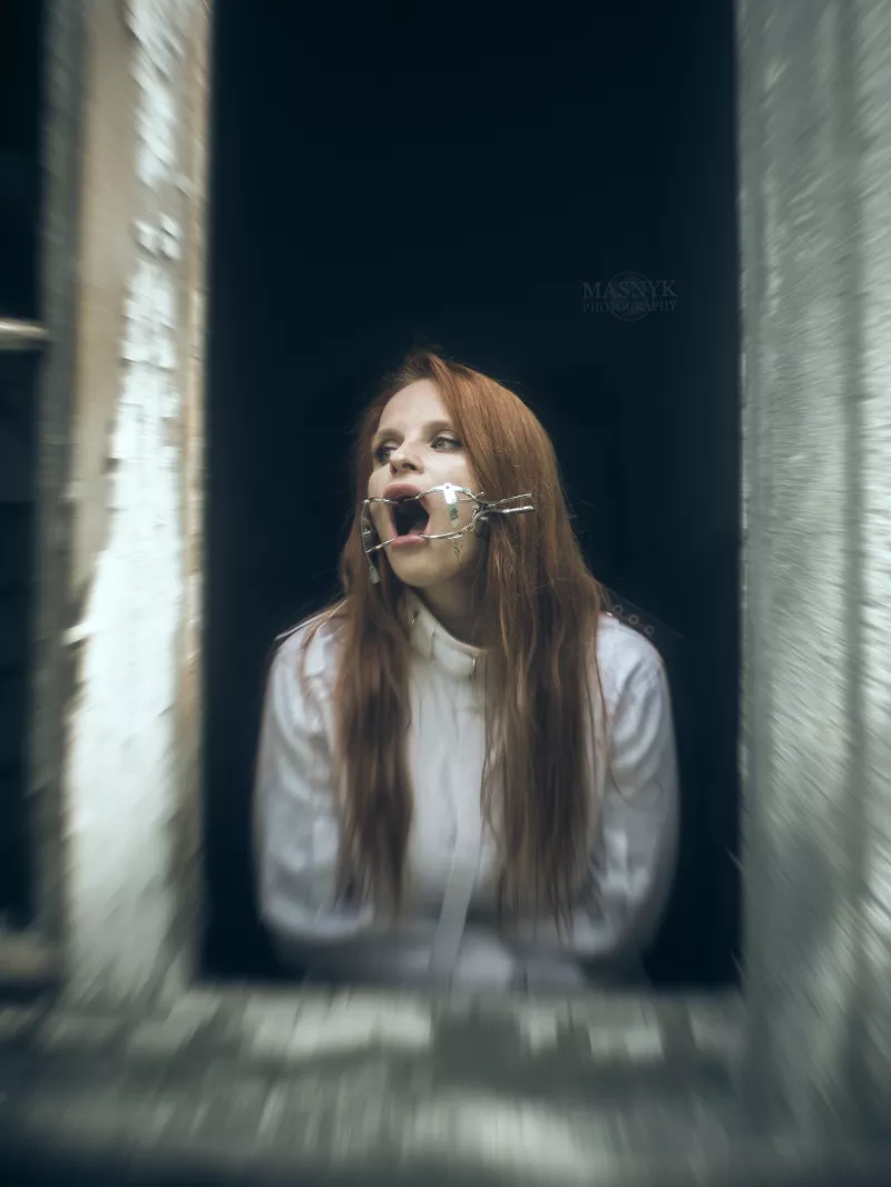 Rudowłosa w kaftanie bezpieczeństwa przy oknie