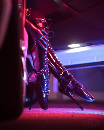 Stilvolle Stiefel mit hohen Absätzen in einem neonbeleuchteten Autoinnenraum