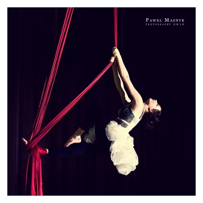 A young woman dances on a hanging fabric.