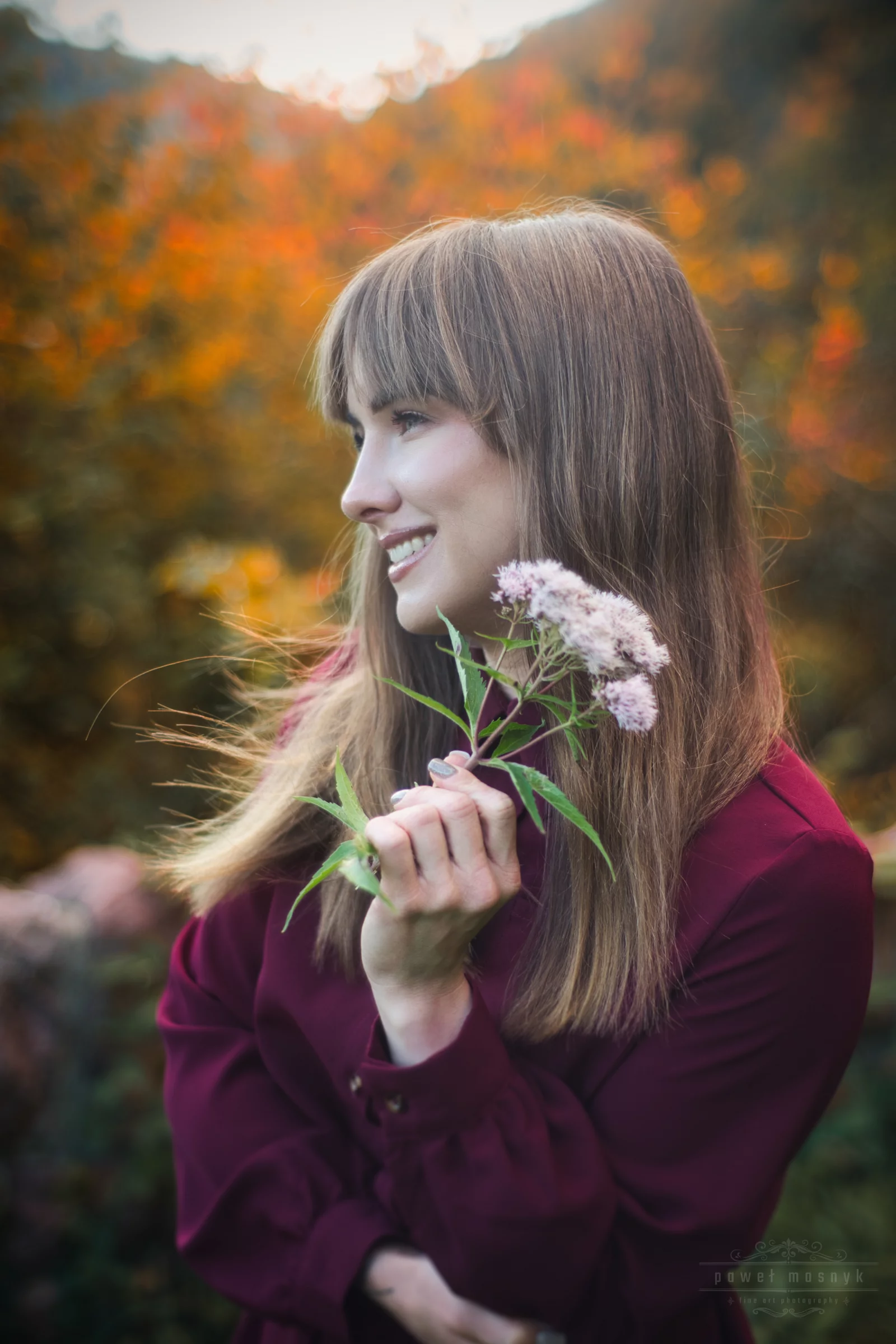 Porträt einer Frau mit einer Blume vor herbstlichen Blättern