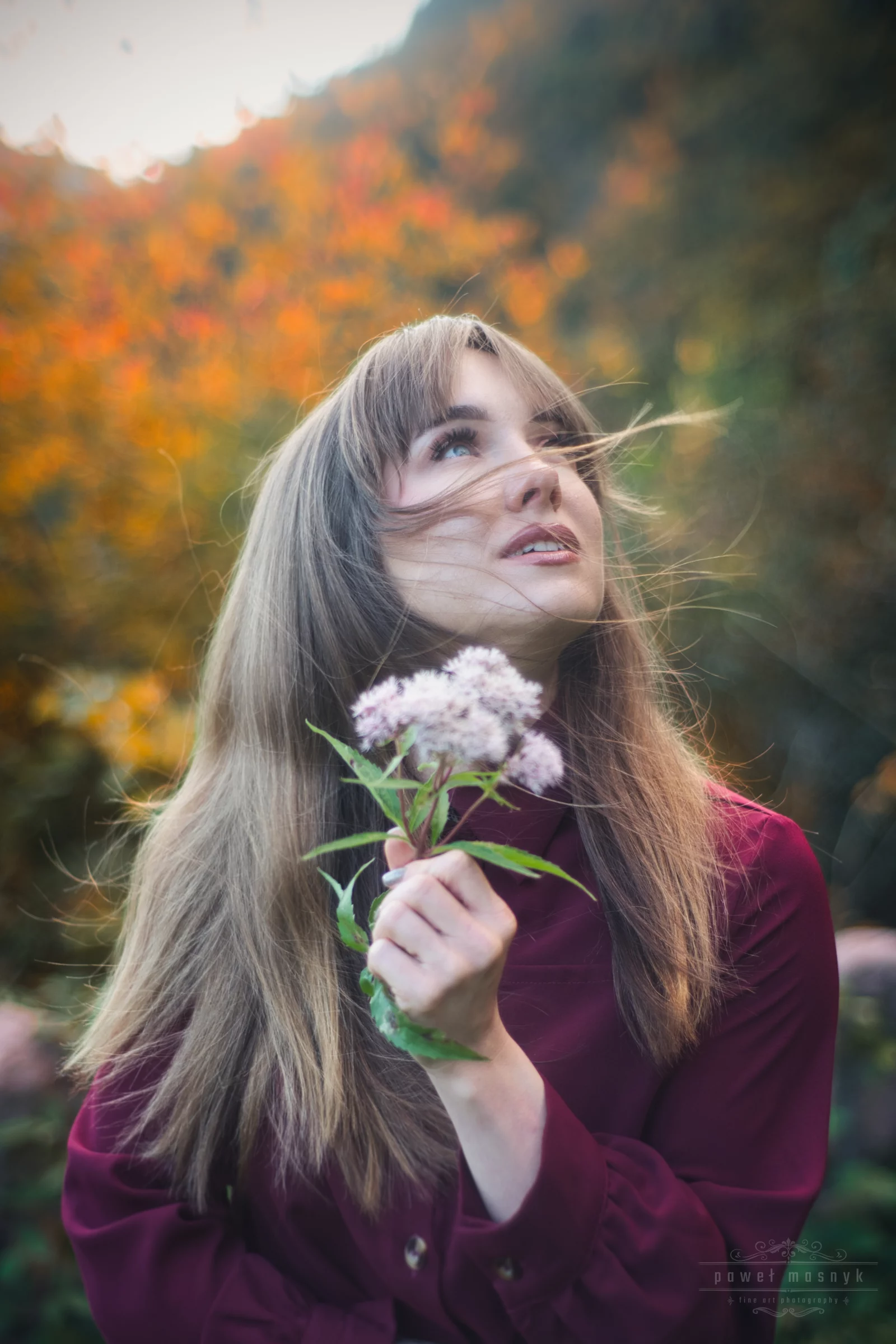 Porträt einer Frau mit einer Blume vor herbstlichen Blättern