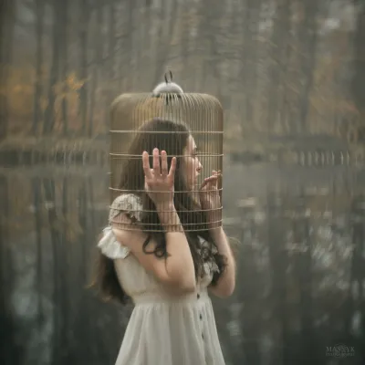 Beautiful woman in white dress locked in bird cage