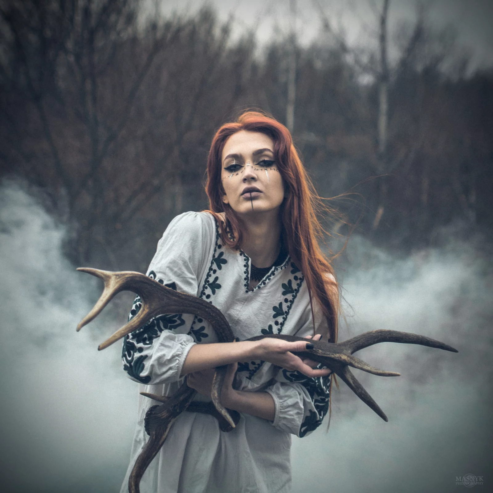Artistic portrait of a woman in nature, holding antlers
