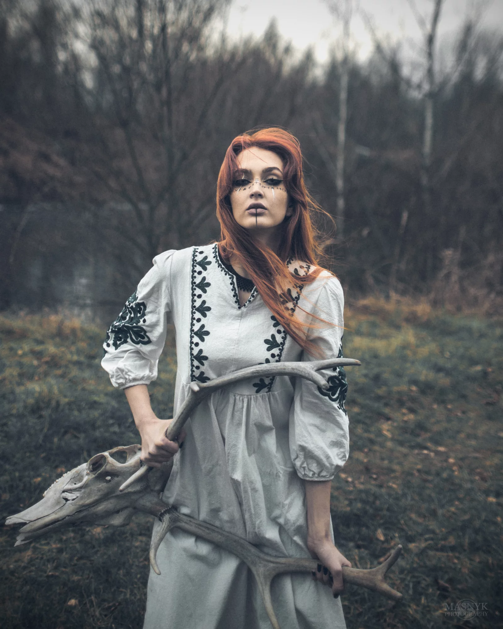 Artistic portrait of a woman in nature, holding antlers