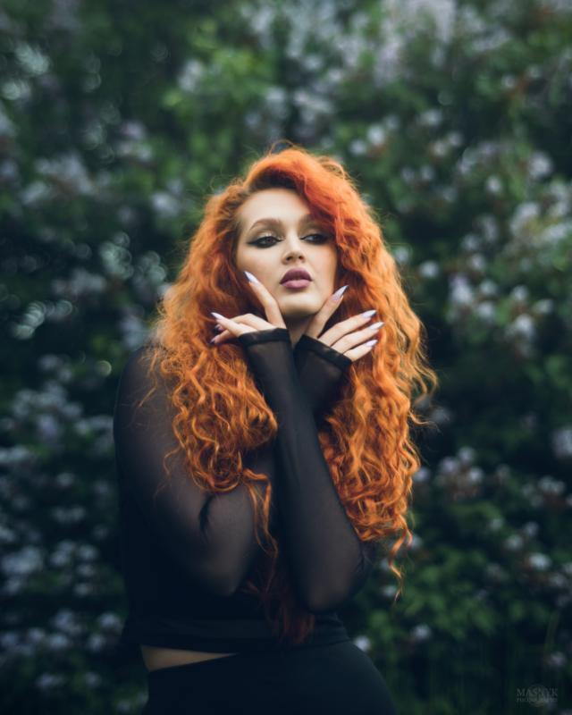A red-haired girl gazes thoughtfully ahead, in a sensual pose.