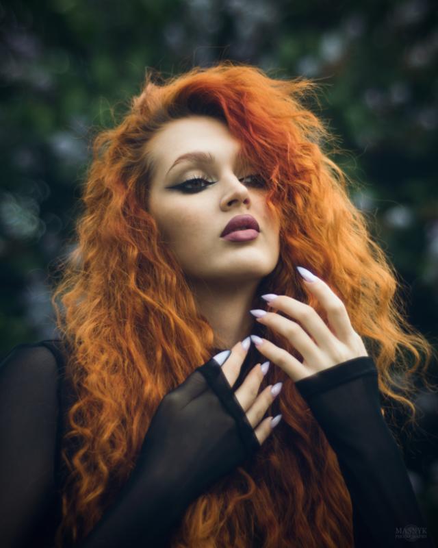 Woman with long curly red hair and black mesh top