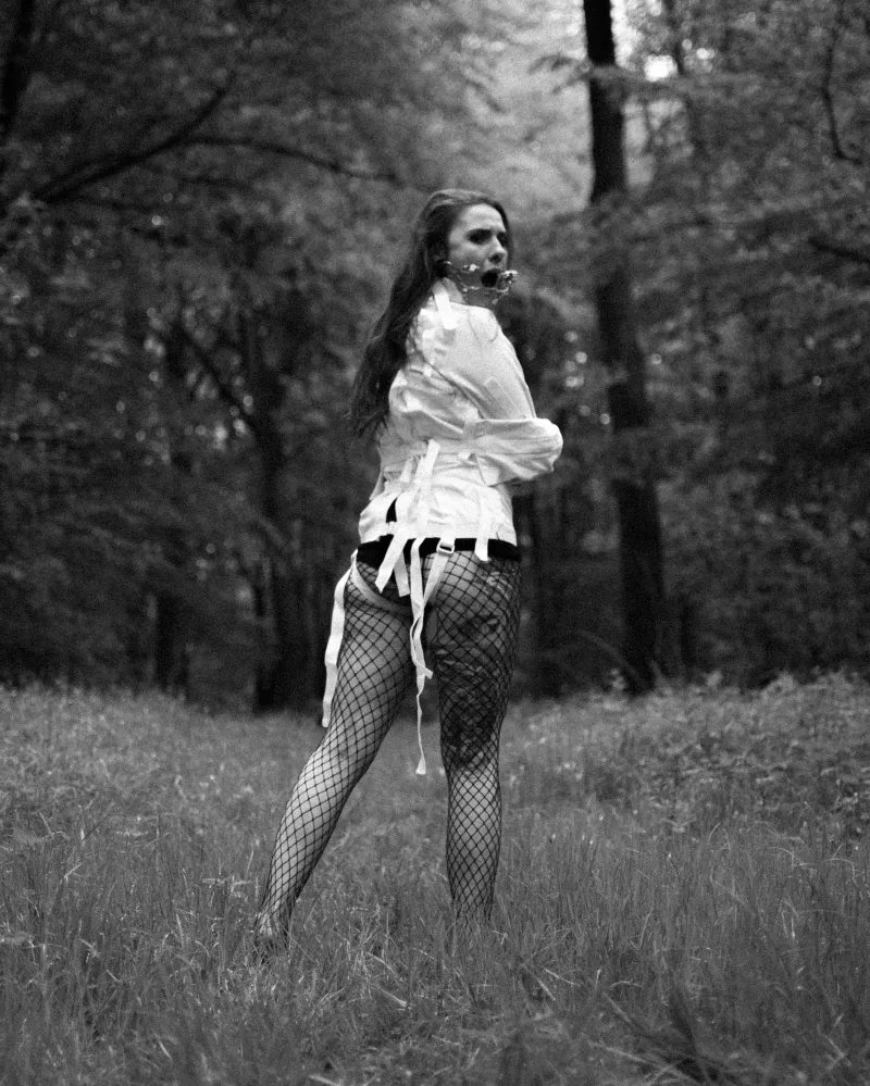 Kobieta w kaftanie bezpieczeństwa z kneblem w lesie