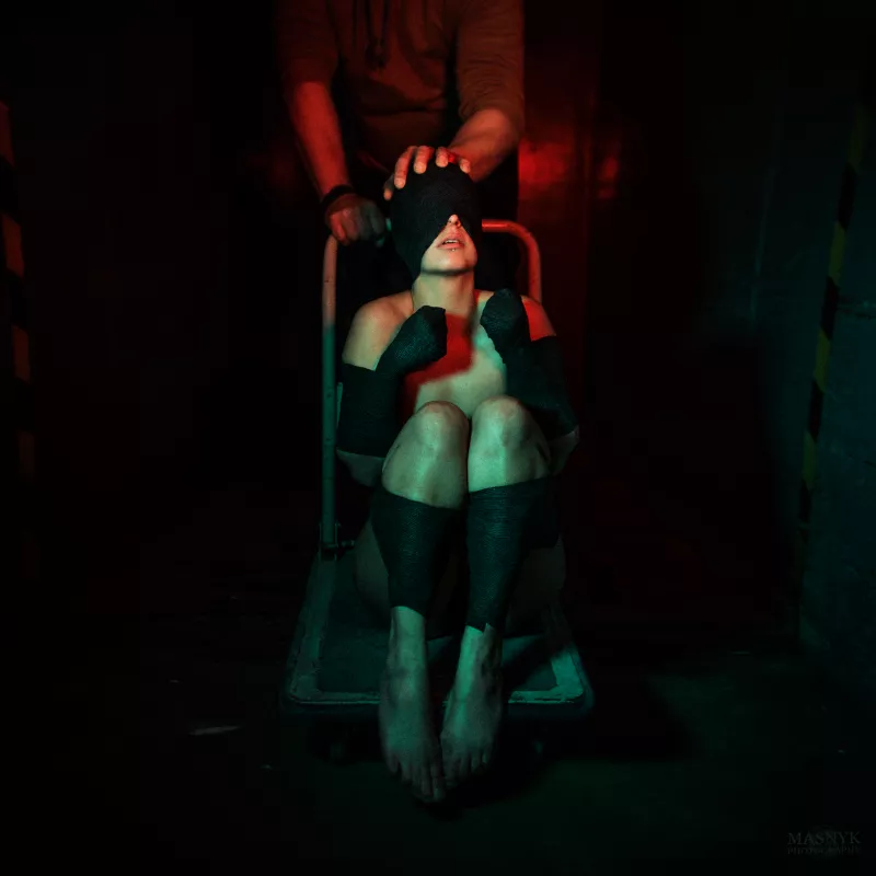 Dark urban exploration and bondage scene with a blindfolded person