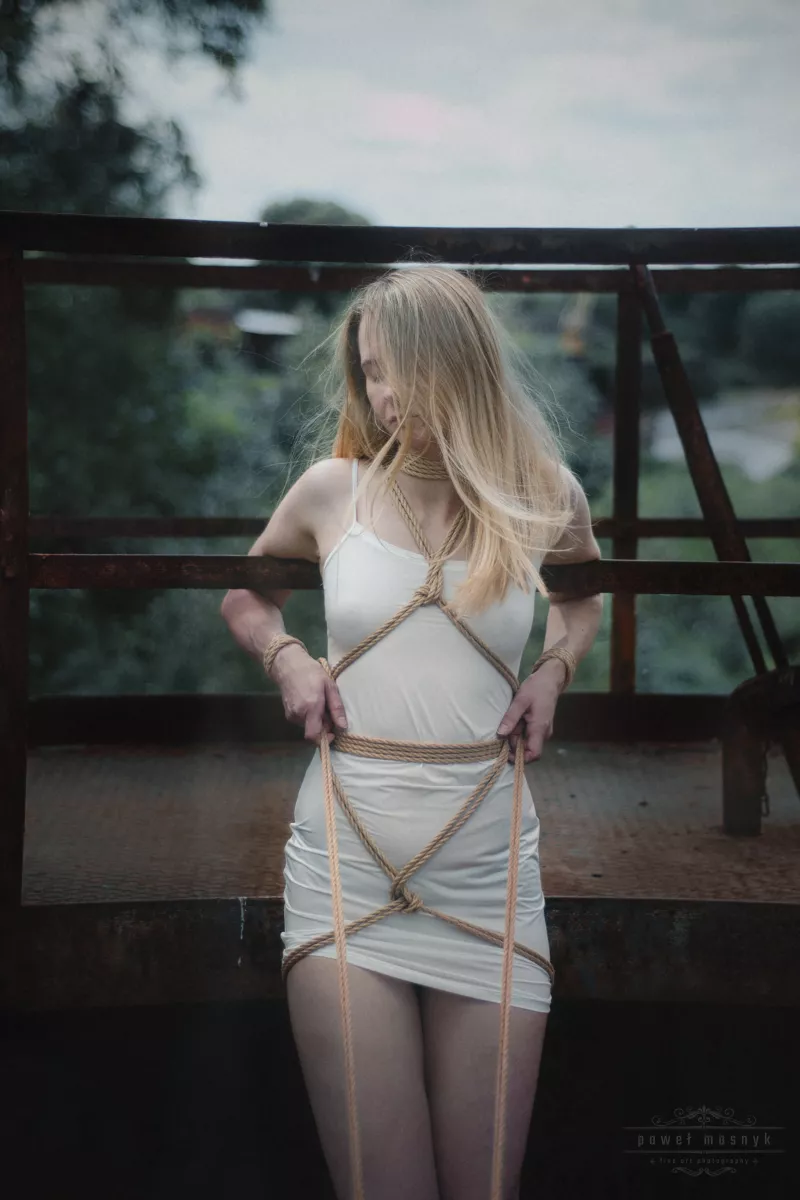 Frau in Shibari-Seilen auf Metallkonstruktion
