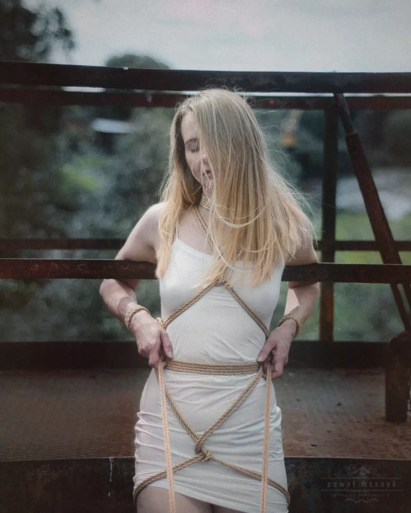 Frau in Shibari-Seilen auf Metallkonstruktion
