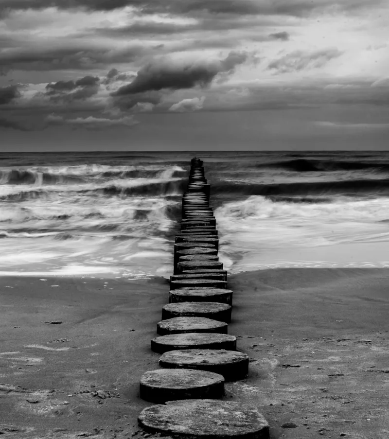 Plaża Dziwnówek, falochrony w dziwnówku i wzburzone morze.