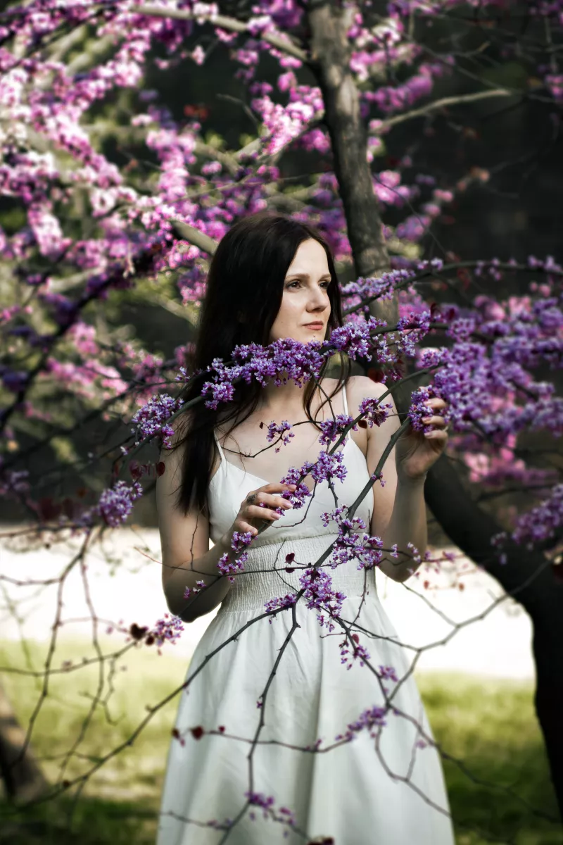 Kobieta w białej sukience otoczona fioletowymi kwiatami