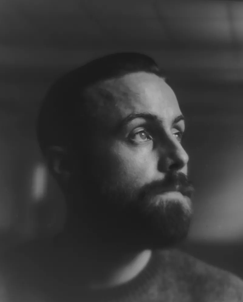 Schwarz-Weiß-Porträt eines bärtigen Mannes, der in die Ferne schaut