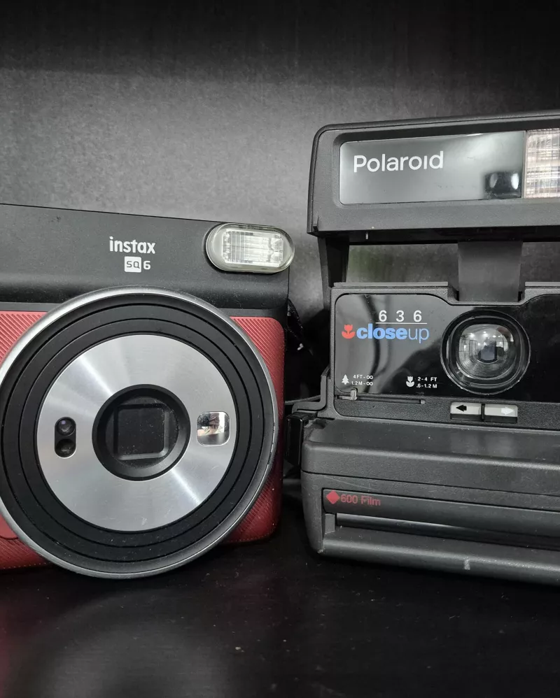Foto einer Instax- und Polaroid-Kamera nebeneinander