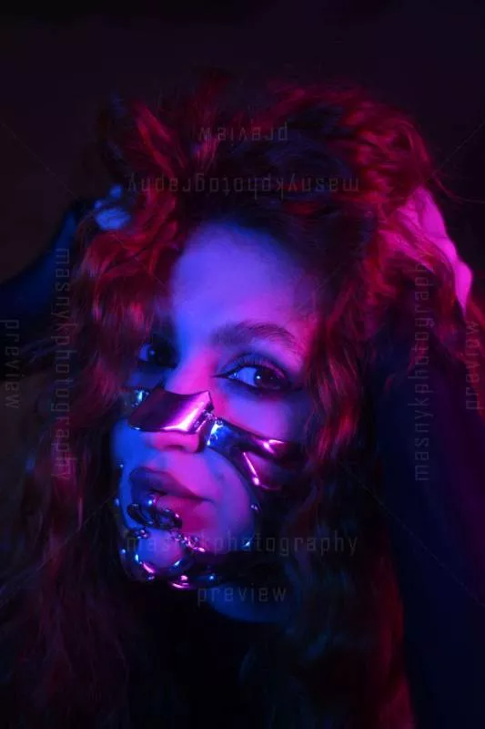 Porträt mit metallischem Gesichtszubehör und bunter Beleuchtung