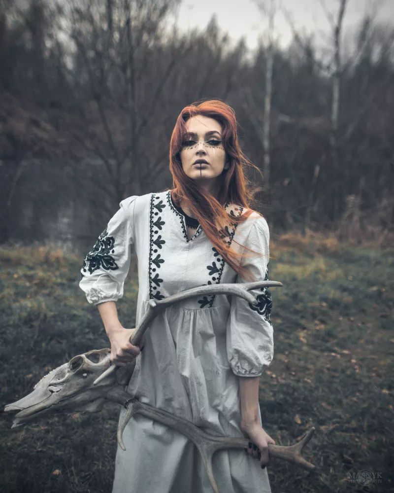 Artistic portrait of a woman in nature, holding antlers