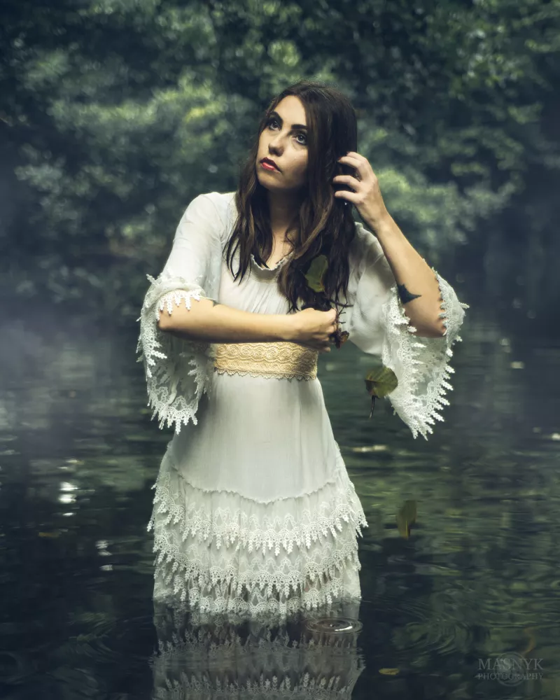 A woman bathes in a lake shrouded in fog.