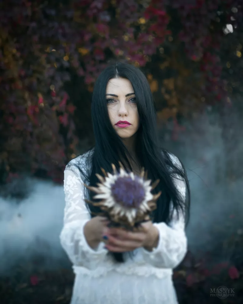 Schöne Frau steht im Nebel und hält eine Blume