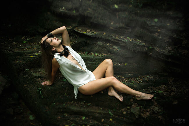 A young woman poses on rocks in a ravine