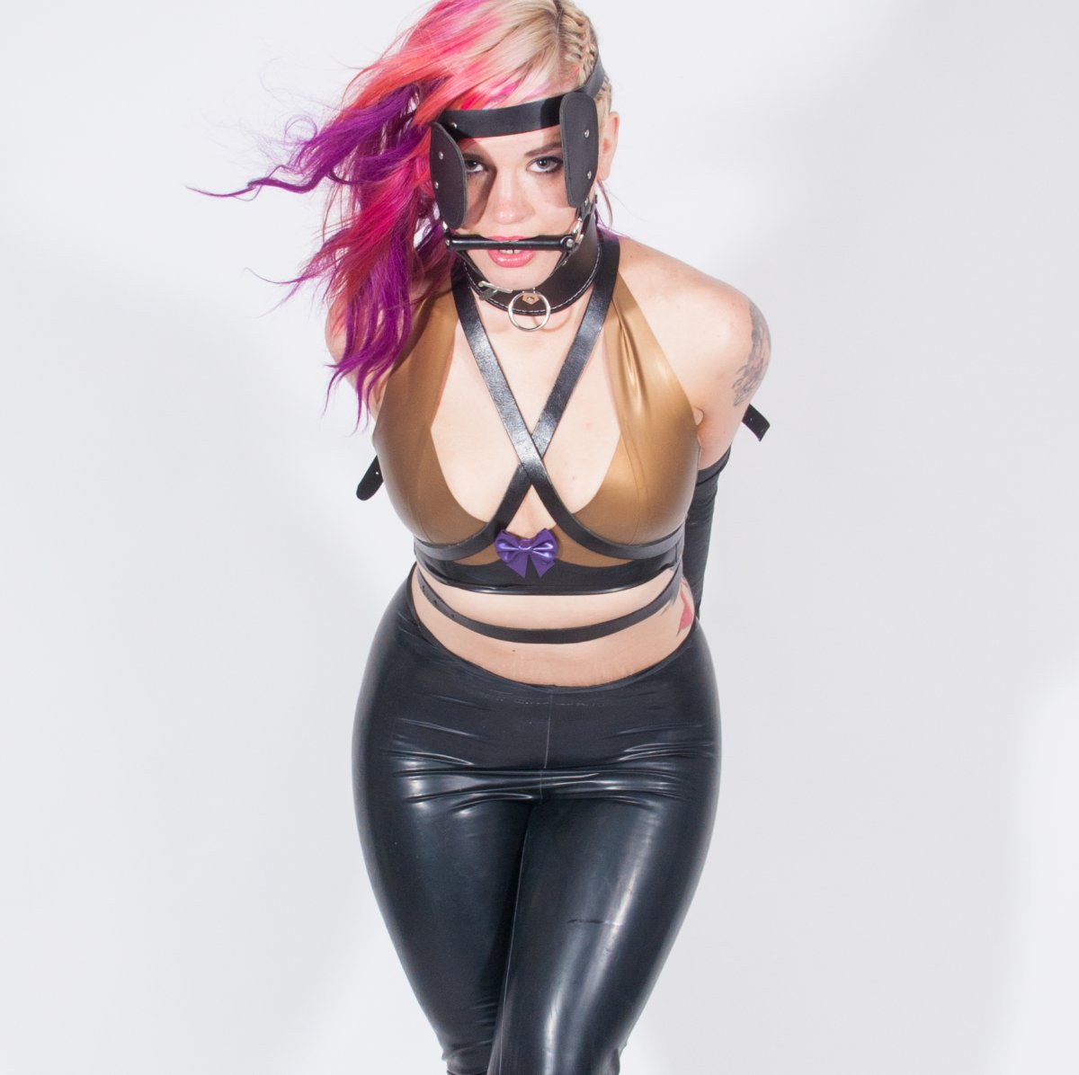 Zakneblowana kobieta w latexowym stroju w roli pony girl