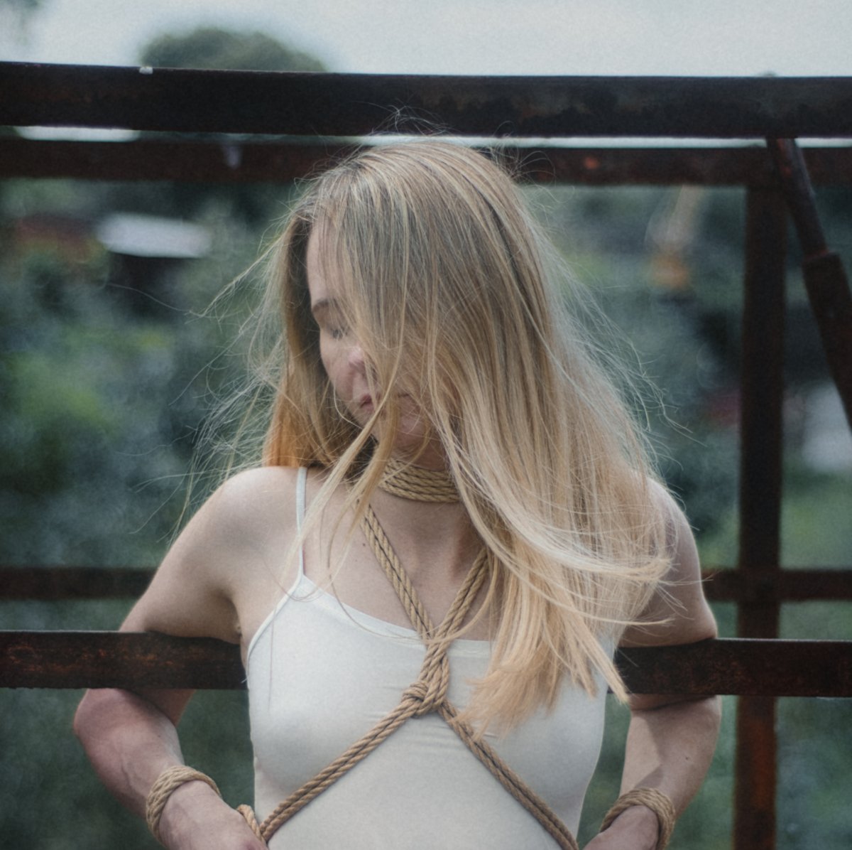 Frau in Shibari-Seilen auf Metallkonstruktion