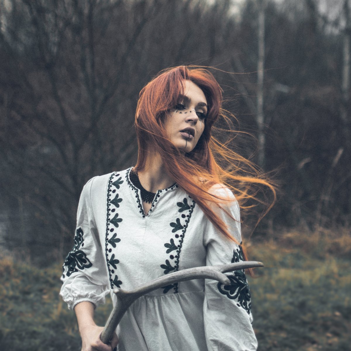Artistic portrait of a woman in nature, holding antlers