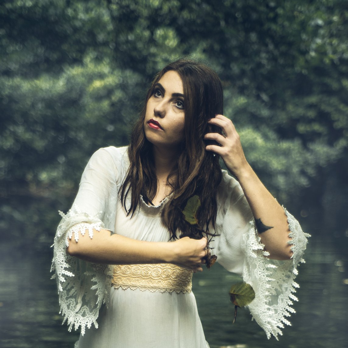 A woman bathes in a lake shrouded in fog.