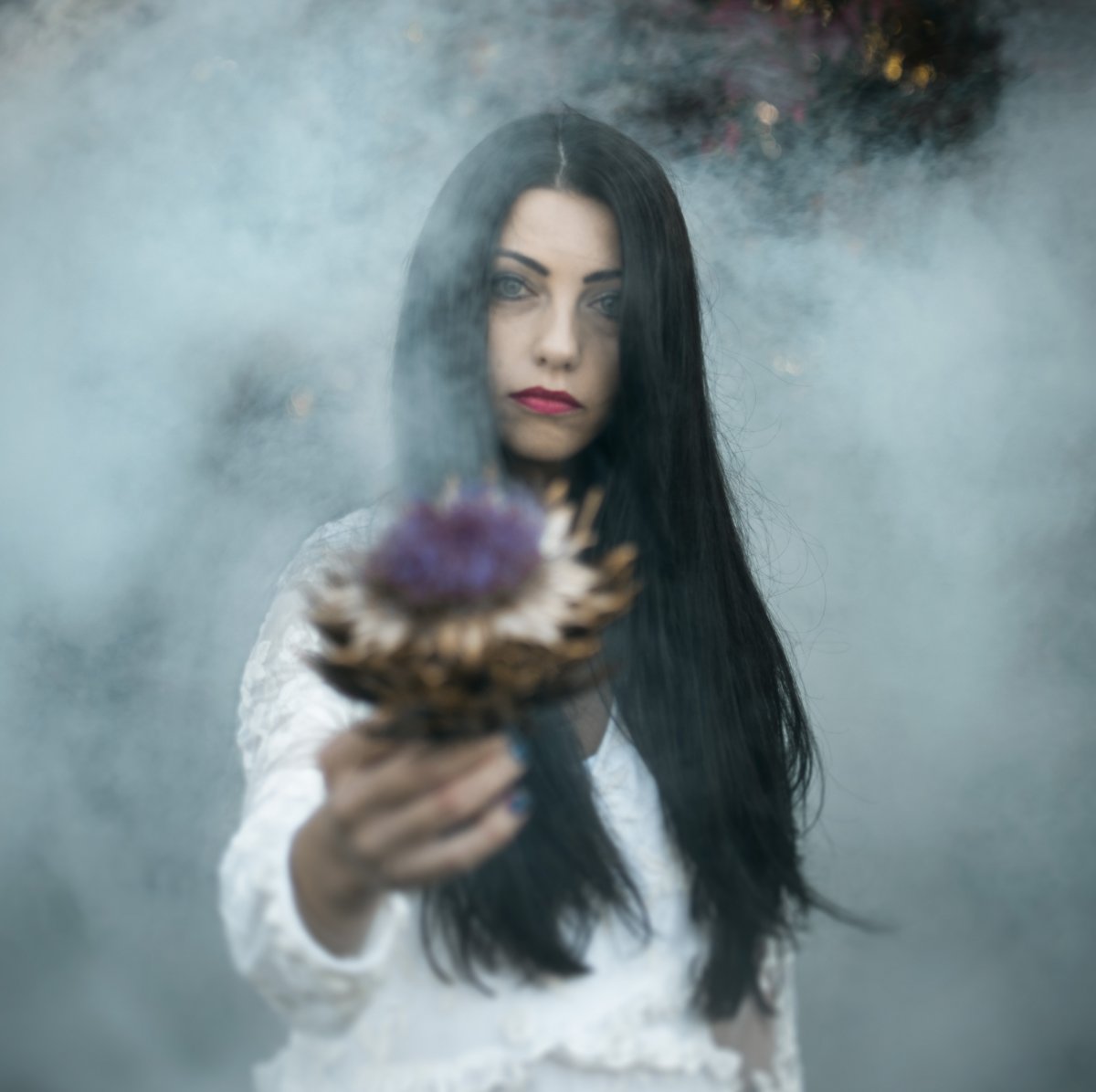 Kobieta w długich włosach i białej sukience stoi we mgle